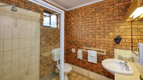 a bathroom with a white sink and a brick wall at The Cottage Motor Inn Albury CBD in Albury