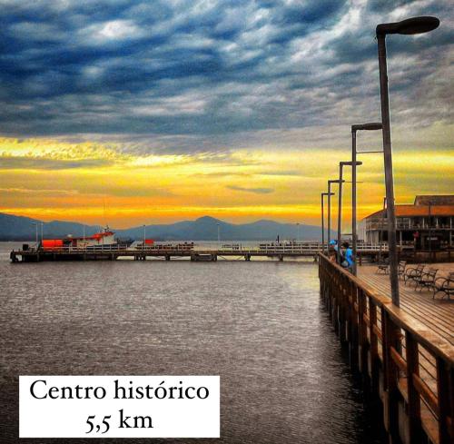 a pier with the sun setting over the water at Cabana Monte Trigo in São Francisco do Sul