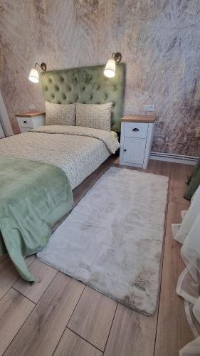 a bedroom with a bed with a green headboard and a rug at Central Residence in Bacău