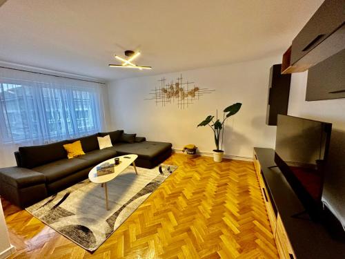 a living room with a black couch and a table at ESI Apartments #Central in Timişoara