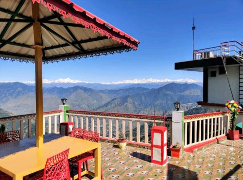 a table and chairs on a balcony with a view of mountains at Hotel Mount View Dhanaulti Dreams in Dhanaulti
