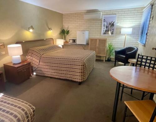 a hotel room with two beds and a table and chairs at Estelle Kramer Motel in Armidale