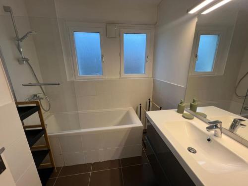 uma casa de banho com uma banheira, um lavatório e um espelho. em Léman Panoramique avec terrasse à deux pas du centre-ville em Évian-les-Bains
