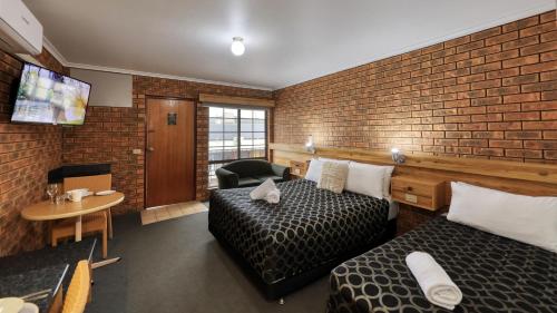 a hotel room with two beds and a tv at The Cottage Motor Inn Albury CBD in Albury
