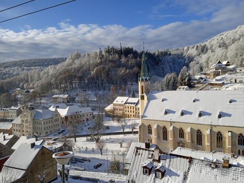 a town with snow covered roofs and a church at Apartmán Albreit in Jáchymov