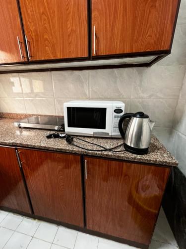 eine Mikrowelle auf einer Theke mit einer Kaffeekanne in der Unterkunft كورنيش عجمان in Ajman 