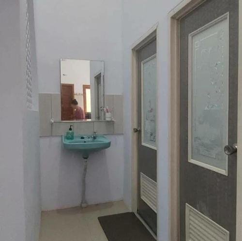 ein Badezimmer mit einem Waschbecken und einer Person im Spiegel in der Unterkunft Soraya Homestay in Tulungagung