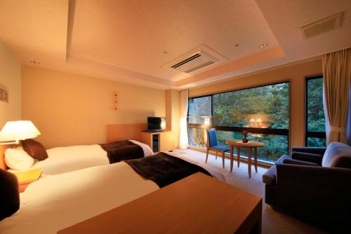a hotel room with two beds and a large window at Hotel Shikisai in Nikko