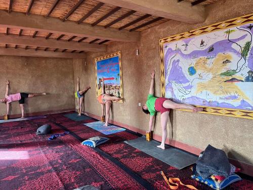 un gruppo di persone che fa una posa yoga in una stanza di Desert Tours & Camp Chraika a M'Hamid