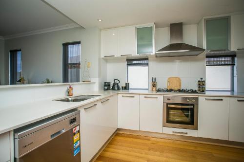 a kitchen with white cabinets and stainless steel appliances at CHILLAX HOUSE - Luxury, Canals, Jetty, Family Friendly - Sleeps 14 in Style! in Mandurah