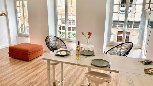 un salon avec une table, des chaises et des fenêtres dans l'établissement Quartier du château, superbe appartement avec parking, à Pau