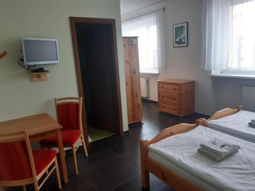 a room with a bed and a table and a tv at Penzion U Dvou lip in Drnholec