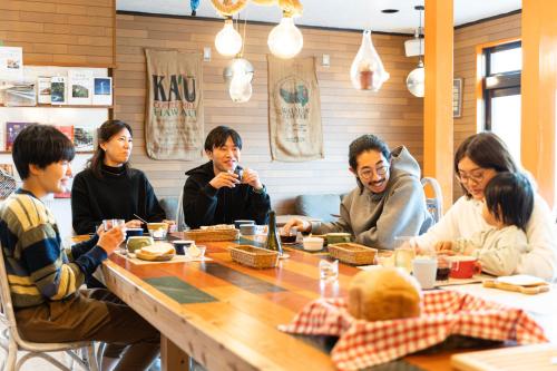 a group of people sitting around a table in a restaurant at Vacation House Familia in Kōzushima