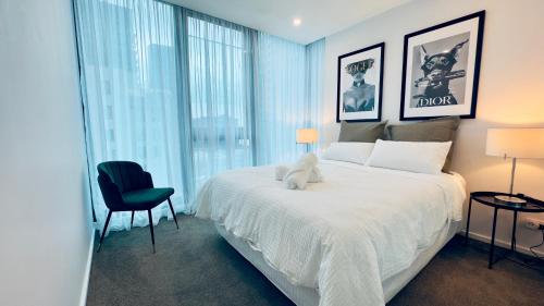 a bedroom with a white bed with a stuffed animal on it at Stylish Southbank apartment Plus Free Parking for 2 Cars in Melbourne