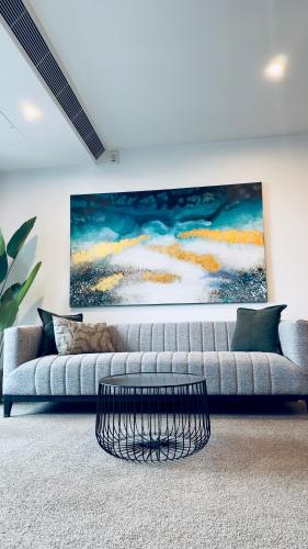 a living room with a couch and a painting on the wall at Stylish Southbank apartment Plus Free Parking for 2 Cars in Melbourne