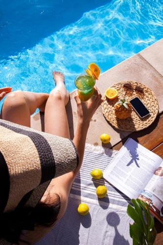 a man sitting on a table with a drink next to a pool at Paternoster Lodge in Paternoster
