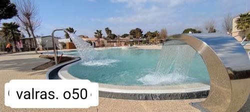 une piscine avec une fontaine au milieu dans l'établissement Mobil'home Valras, à Valras-Plage