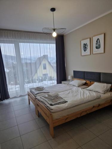 a bedroom with a large bed and a large window at Domki Piecykowo in Międzybrodzie Żywieckie