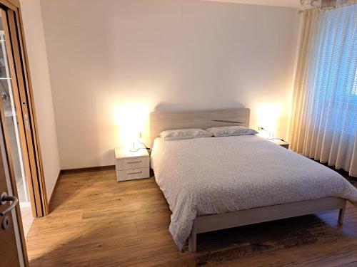 a bedroom with a bed with two lamps and a window at RESIDENZA CADORINA in Calalzo