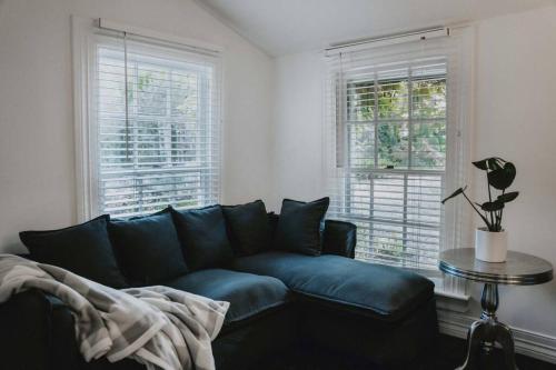 a living room with a blue couch and two windows at Uffington House ~Two bedroom house in Daylesford in Daylesford