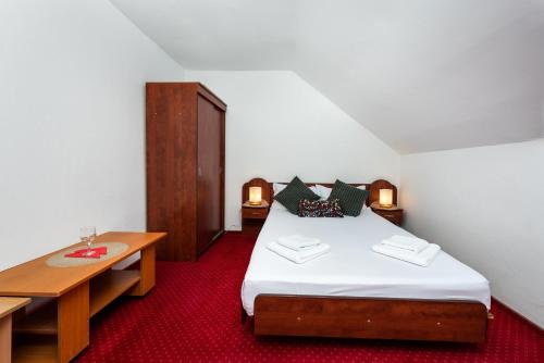 a bedroom with a bed and two tables and a table at Pensiunea Ursuletul Paddington in Predeal