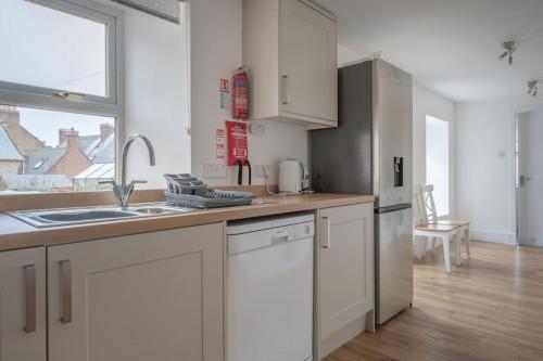 a kitchen with white cabinets and a sink at Beautiful Detached House, just metres from the sea in Gourdon