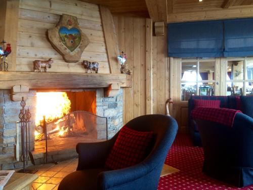 a living room with a fireplace with chairs and a table at Aux Ducs de Savoie in Combloux