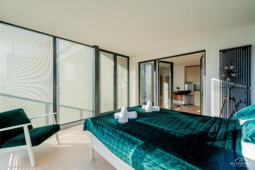 sypialnia z zielonym łóżkiem i krzesłem w obiekcie Horyzont Apartamenty - Wyspa Solna w Kołobrzegu