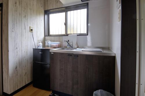 a small kitchen with a sink and a refrigerator at Cottage Kutsuroki in Yakushima