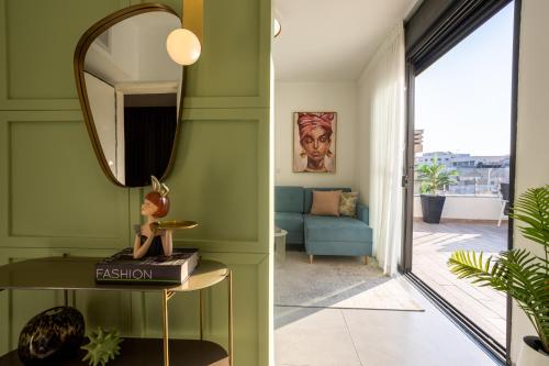 a living room with green walls and a mirror at YalaRent Flora- Designed 1BR penthouse in Florentin in Tel Aviv