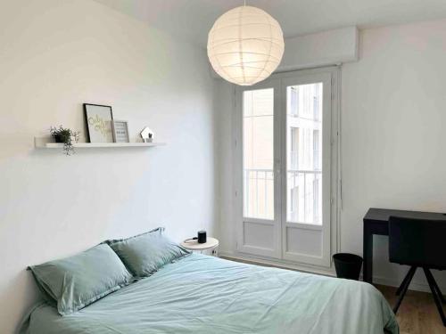 um quarto branco com uma cama e uma grande janela em L' escapade Rémoise - Beau 4 pièces refait à neuf em Reims