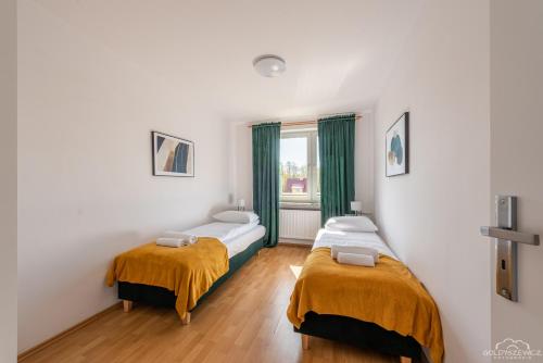 a bedroom with two beds and a window at Horyzont Apartamenty -Domek na Sosnowej z tarasem in Kołobrzeg