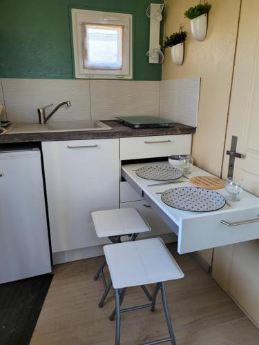 a small kitchen with two stools and a sink at La paillote idyllique in Faverolles-sur-Cher