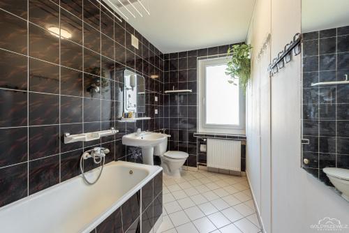 łazienka z wanną, umywalką i toaletą w obiekcie Horyzont Apartamenty -Domek na Sosnowej z tarasem w Kołobrzegu