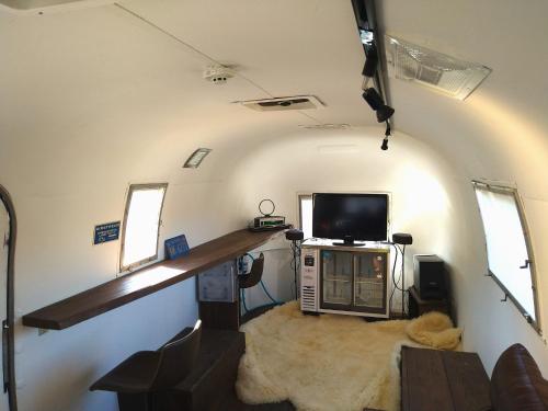 ein Wohnzimmer mit einem TV und einem Schreibtisch in einem Zimmer in der Unterkunft Guest House Uminokyojyusya - Vacation STAY 04260v in Miyazaki