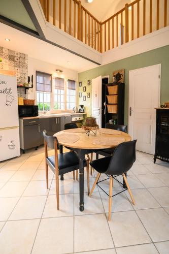 a kitchen with a wooden table and chairs at Gîte Cosy Green in Chevincourt