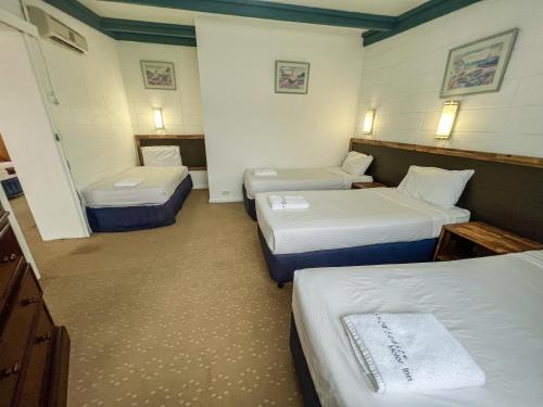 a hotel room with two beds and two tables at Snow Season Motor Inn in Cooma