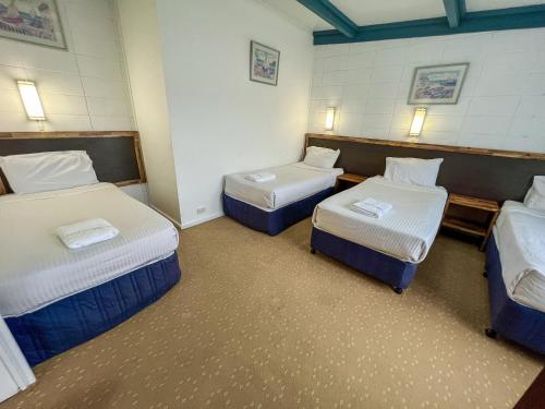 a room with three beds in a room at Snow Season Motor Inn in Cooma