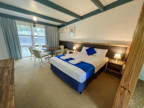 a hotel room with a bed and a table and chairs at Snow Season Motor Inn in Cooma