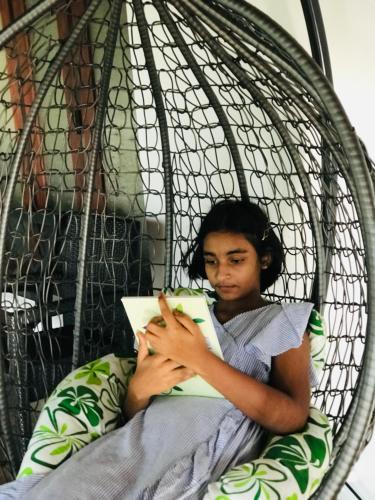 a woman laying in a basket reading a book at Ceylon Kingsmen Garden - Katunayake Airport Transit Hotels in Negombo