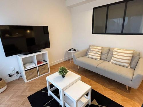 a living room with a couch and a flat screen tv at Sador, Joli appt proche mémorial de Caen in Caen
