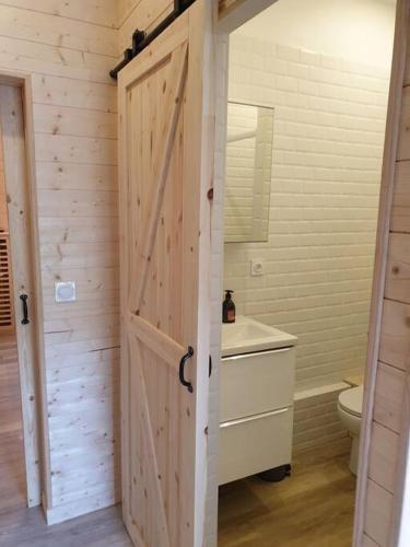 La salle de bains est pourvue d'une porte en bois, de toilettes et d'un lavabo. dans l'établissement Les Iris Véranda Parcking, à Le Mont-Dore