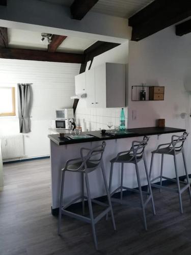 une cuisine avec deux tabourets de bar et un comptoir dans l'établissement Cité des Princes, à Montbéliard