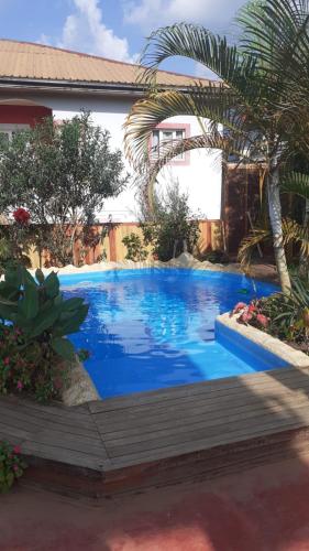 a blue swimming pool in front of a house at Residence Jardin Tropical in Yaoundé