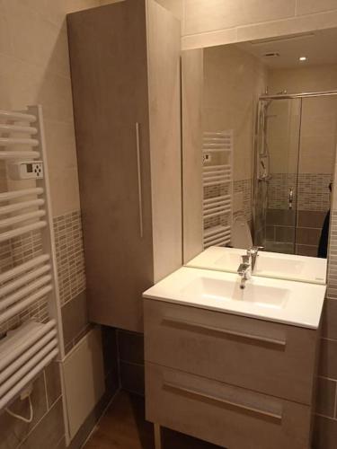 une salle de bain blanche avec un lavabo et un miroir dans l'établissement Maison de Fernand, à Montjay
