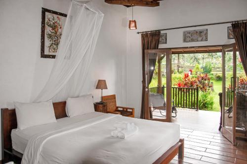 a bedroom with a bed and a door to a patio at Amartya Puri Green Cottages in Munduk