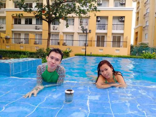 a man and a girl laying in a swimming pool at Two-Bedroom at San Remo Oasis in Cebu City