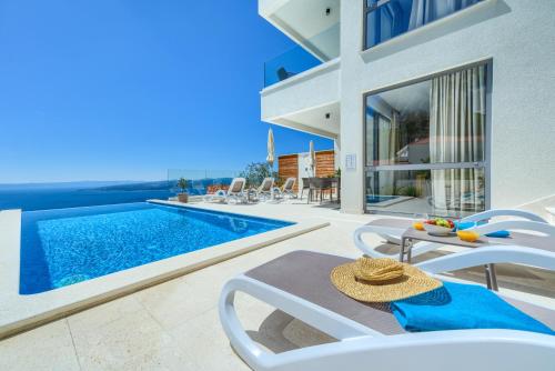 a villa with a swimming pool with a table and chairs at Villa Bellevue Bast in Baška Voda