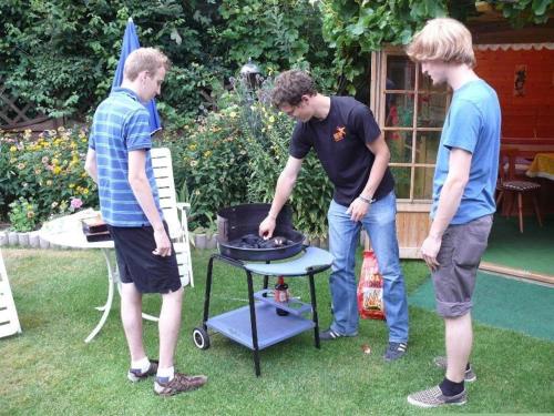 a group of three men standing around a grill at Komfort-Ferienwohnung-BURCK-97-qm-3-Schlafzimmer-2-WC in Wankendorf