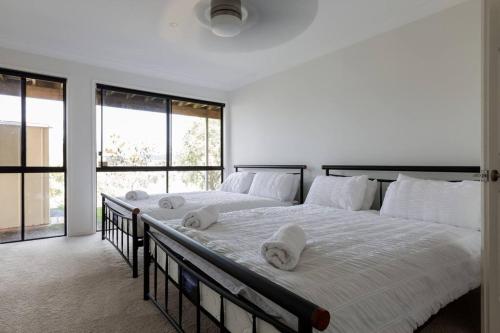 1 dormitorio con 1 cama grande con sábanas blancas y ventanas en Gold Coast Theme Parks With a Pool, en Gold Coast